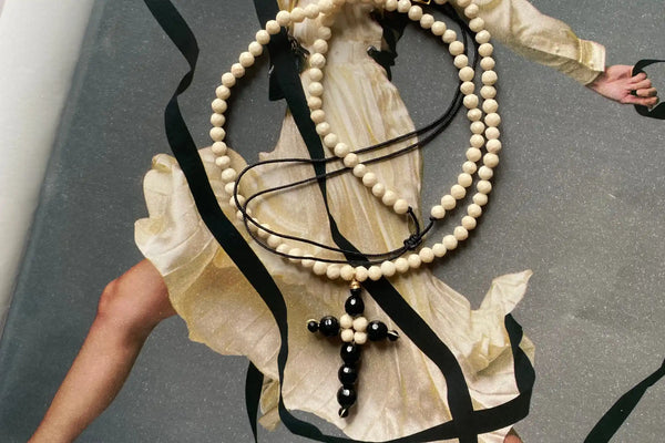 Chapelet blanc en perles avec croix noire et corde en cuir.