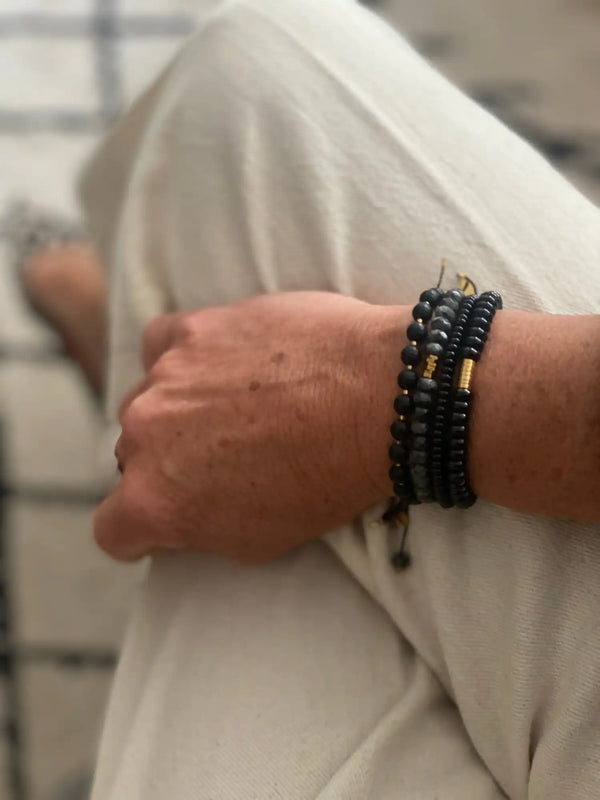 Bracelet en perles noires avec des accents en or et un petit pendentif.