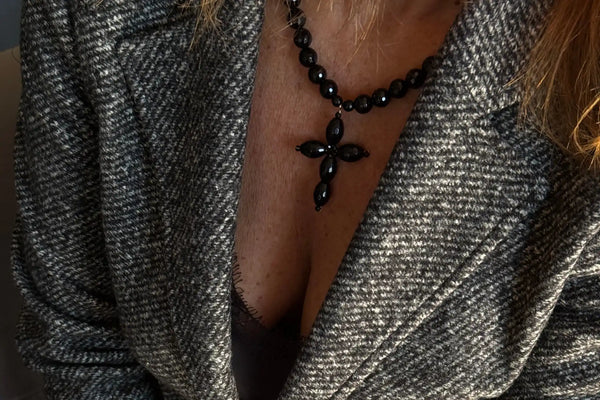 Collier avec croix en perles noires et pendentif central.